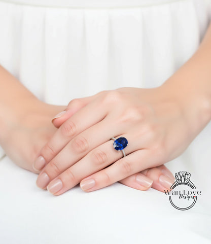 A close-up image of a person's hands wearing a ring with a large blue gemstone.