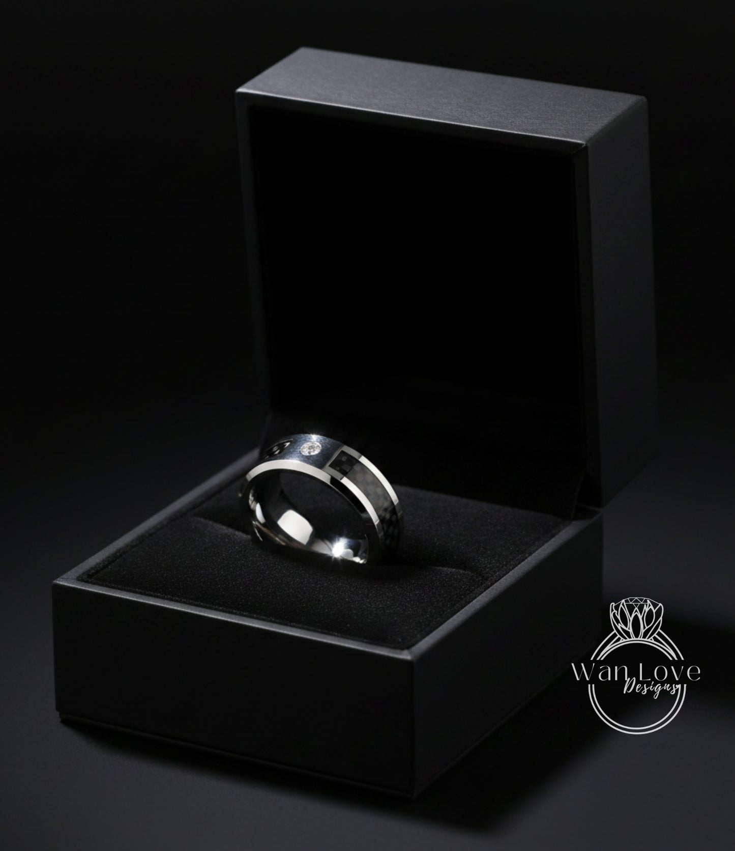 A silver ring is displayed in a black jewelry box against a dark background.