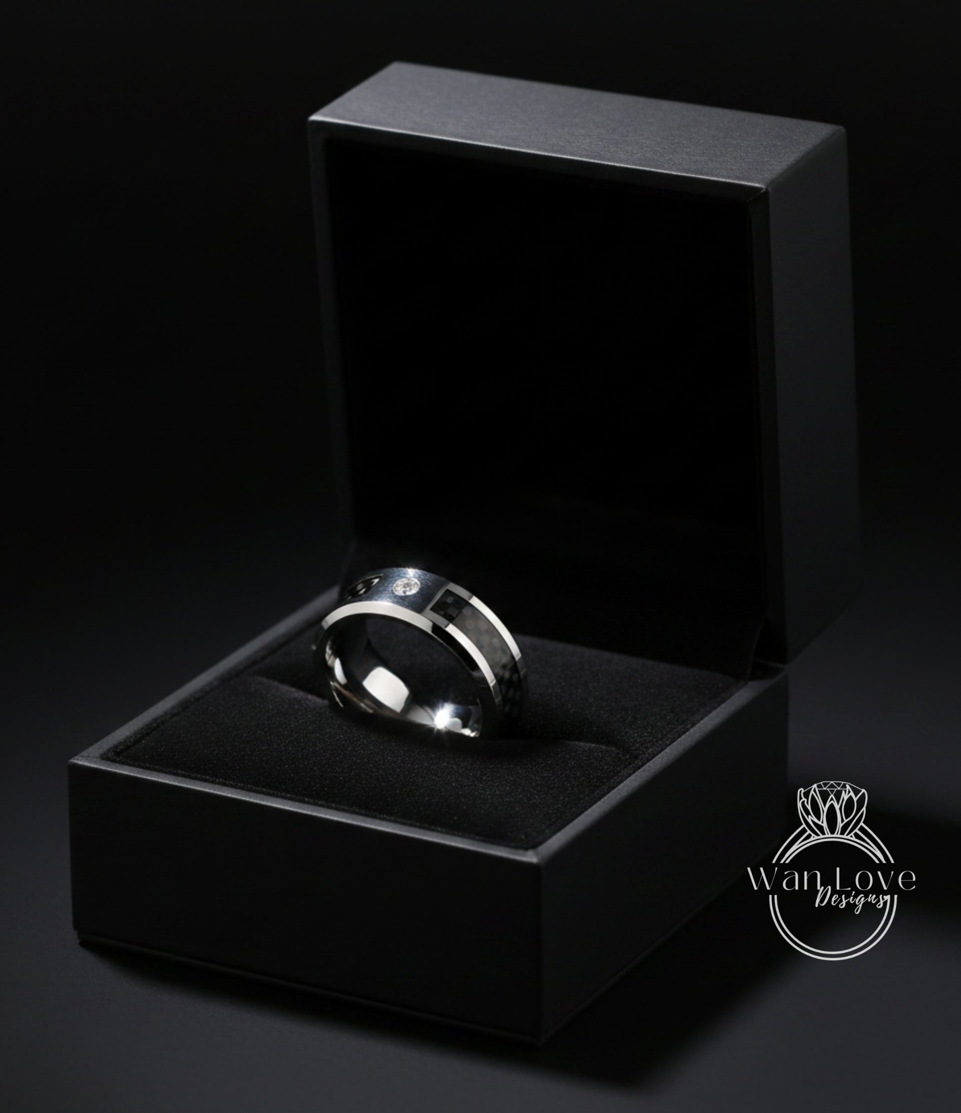 A silver ring is displayed in a black jewelry box against a dark background.