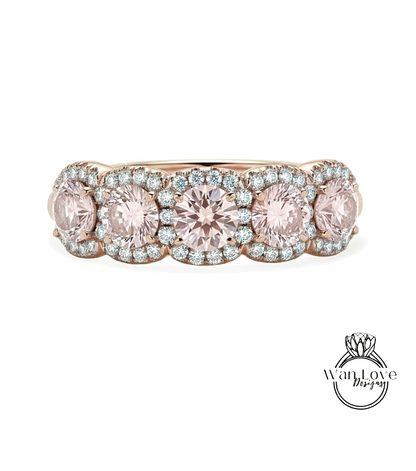 A gold ring with a row of pink gemstones set in the center, surrounded by smaller diamonds.