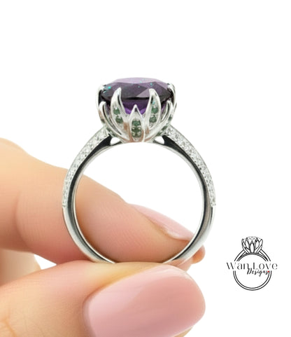 A close-up image of a person's hand holding a silver ring with a large purple gemstone, likely an amethyst, on the ring.