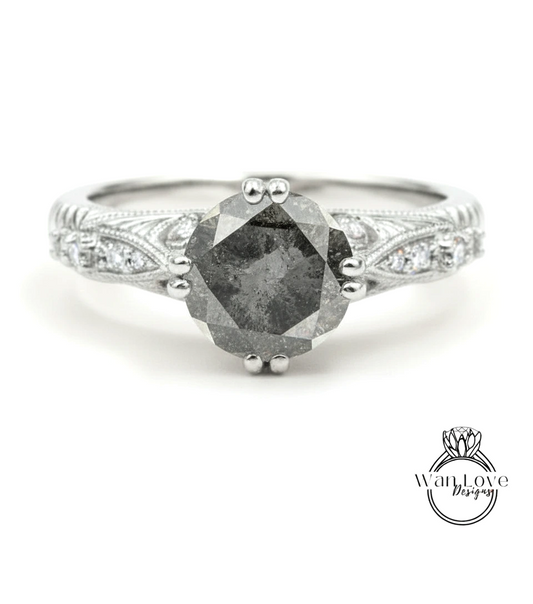 A silver engagement ring with a large, dark gray diamond as the centerpiece, surrounded by smaller diamonds and intricate designs.