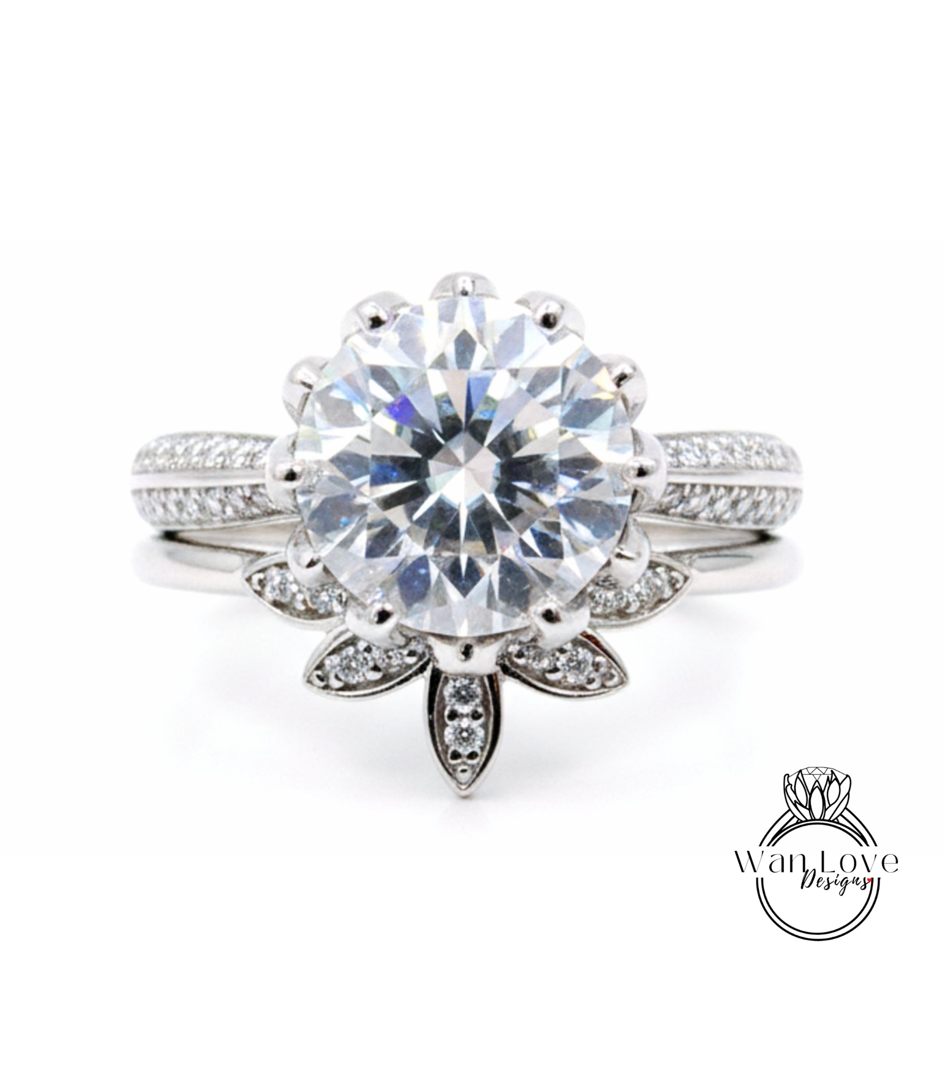 A stunning diamond engagement ring with a large central diamond surrounded by smaller diamonds on either side, set in a silver band with a leaf-shaped accent.