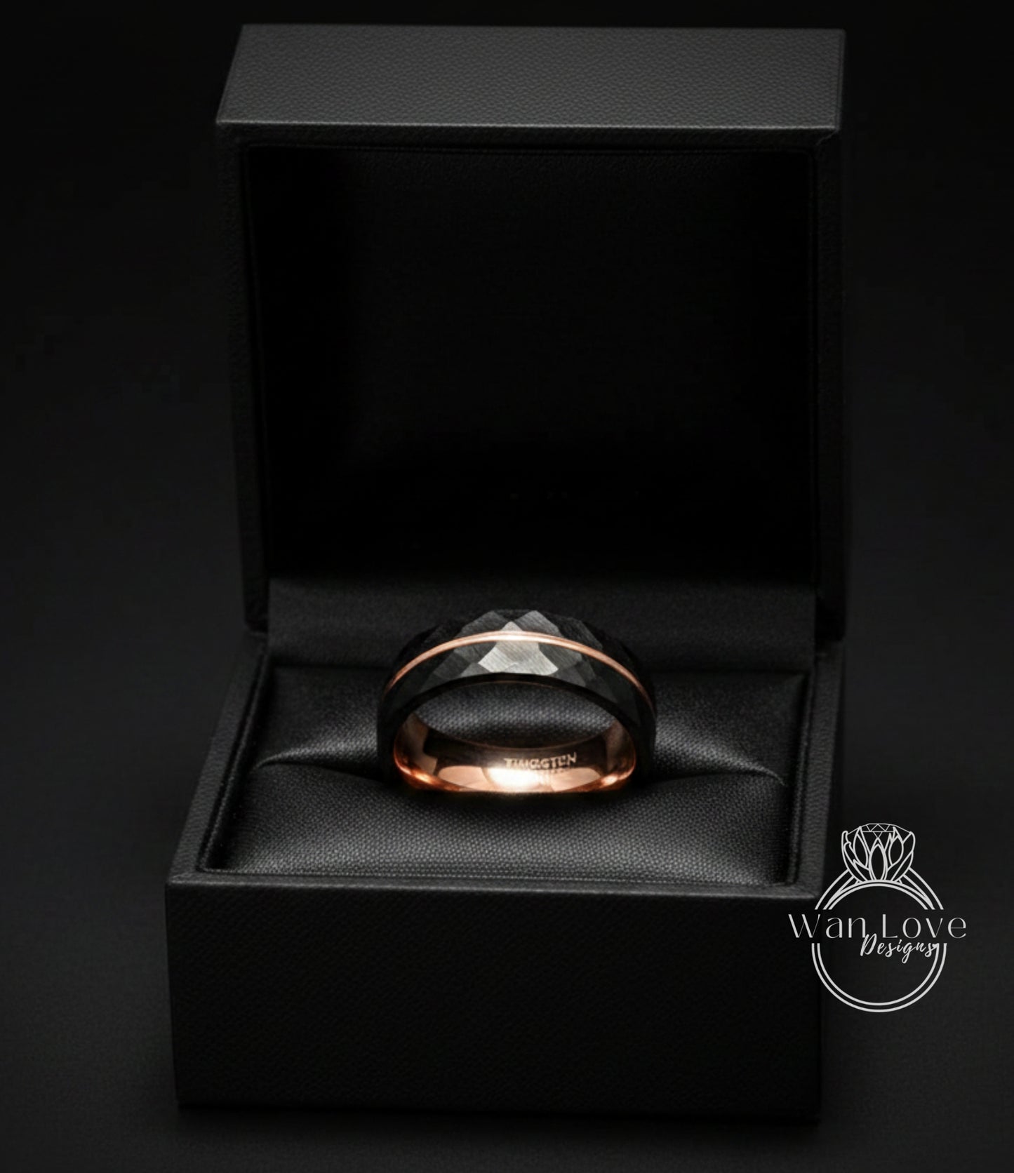 A black jewelry box containing a black and gold ring.