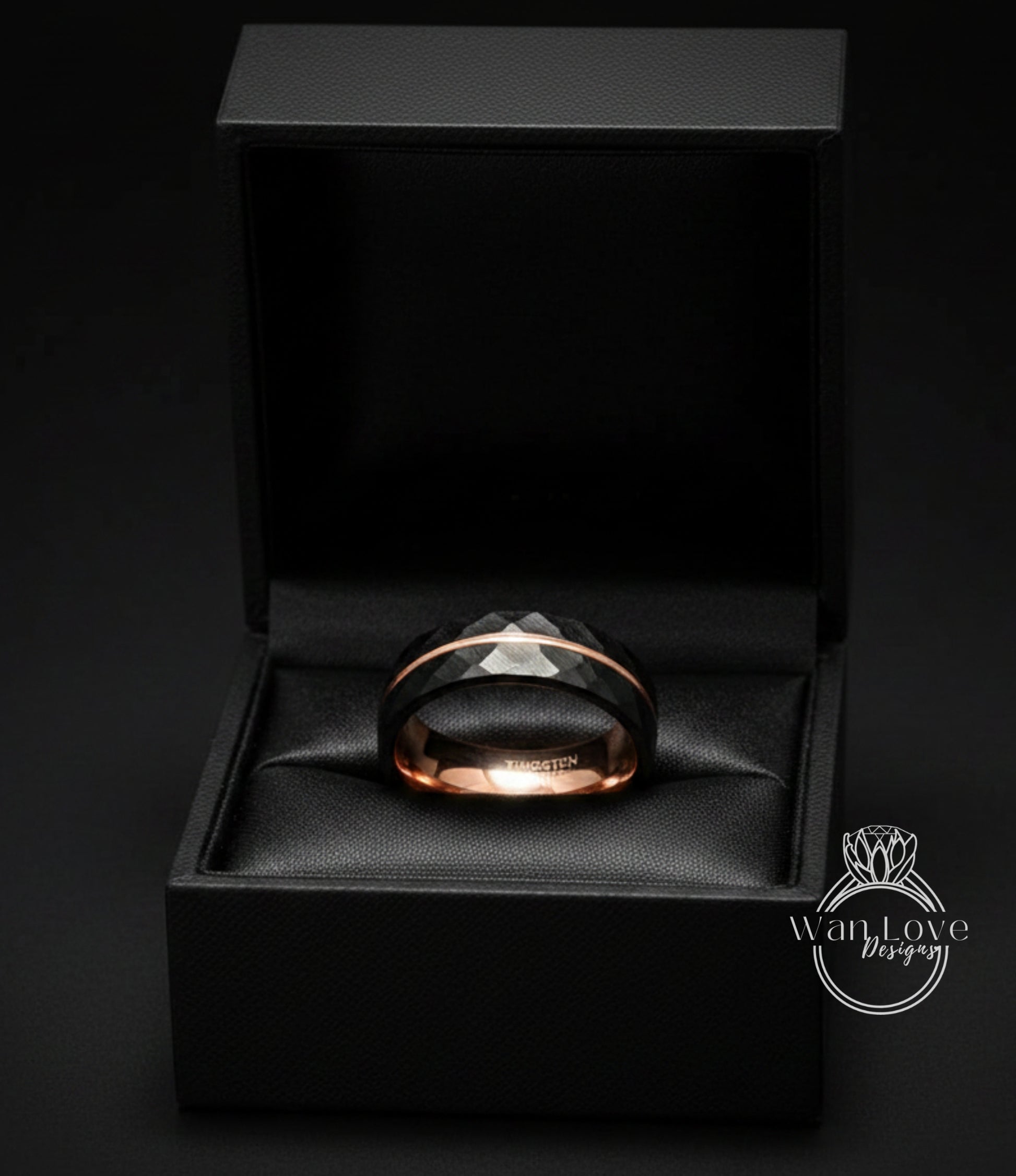 A black jewelry box containing a black and gold ring.