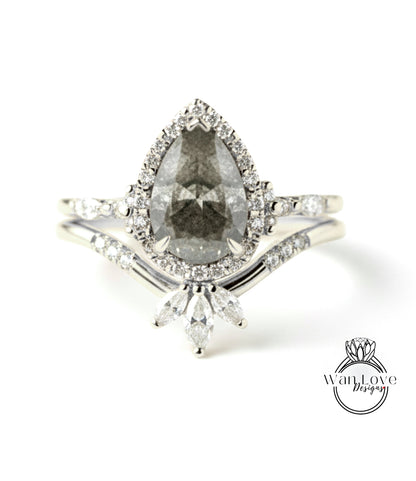 A close-up image of a diamond engagement ring with a large pear-shaped diamond at the center, surrounded by smaller diamonds and set in a halo of smaller diamonds.