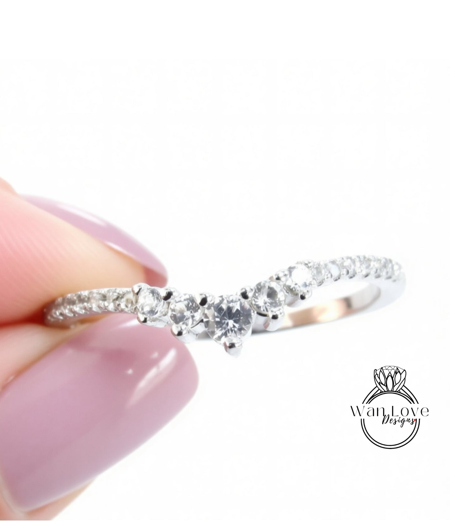 A close-up image of a person's hand holding a silver ring with a diamond-encrusted band.