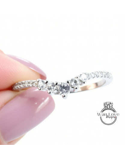 A close-up image of a person's hand holding a silver ring with a diamond-encrusted band.