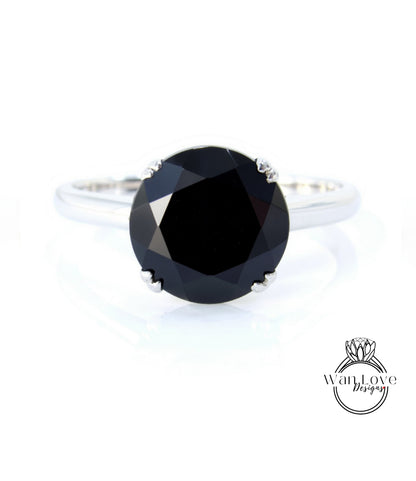 A silver ring with a large, round black diamond as the centerpiece.