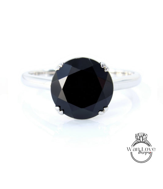 A silver ring with a large, round black diamond as the centerpiece.