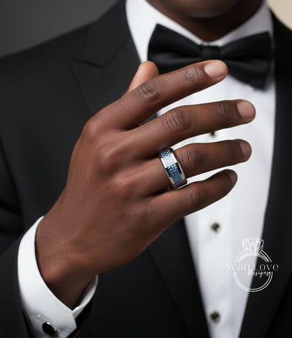 A close-up of a man's hand wearing a ring, with a black suit and bow tie visible.