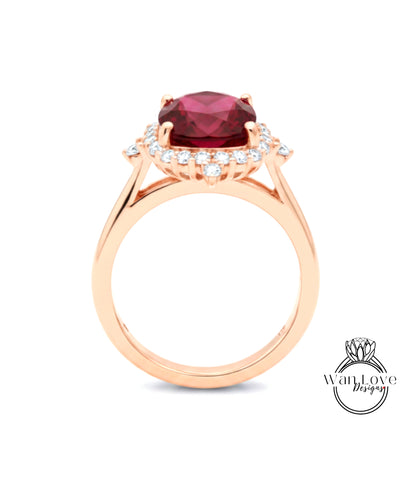 A gold ring with a large red gemstone, likely a ruby, set in a halo of smaller diamonds.