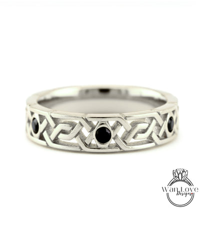 A silver band ring with a geometric design and three black gemstones.