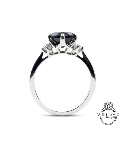 A silver engagement ring with a large black gemstone, possibly a diamond, set in the center.