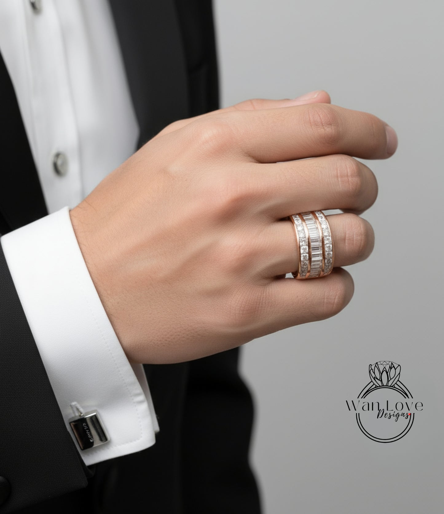 A close-up of a person's hand wearing a ring and cufflinks, with a black suit jacket visible.