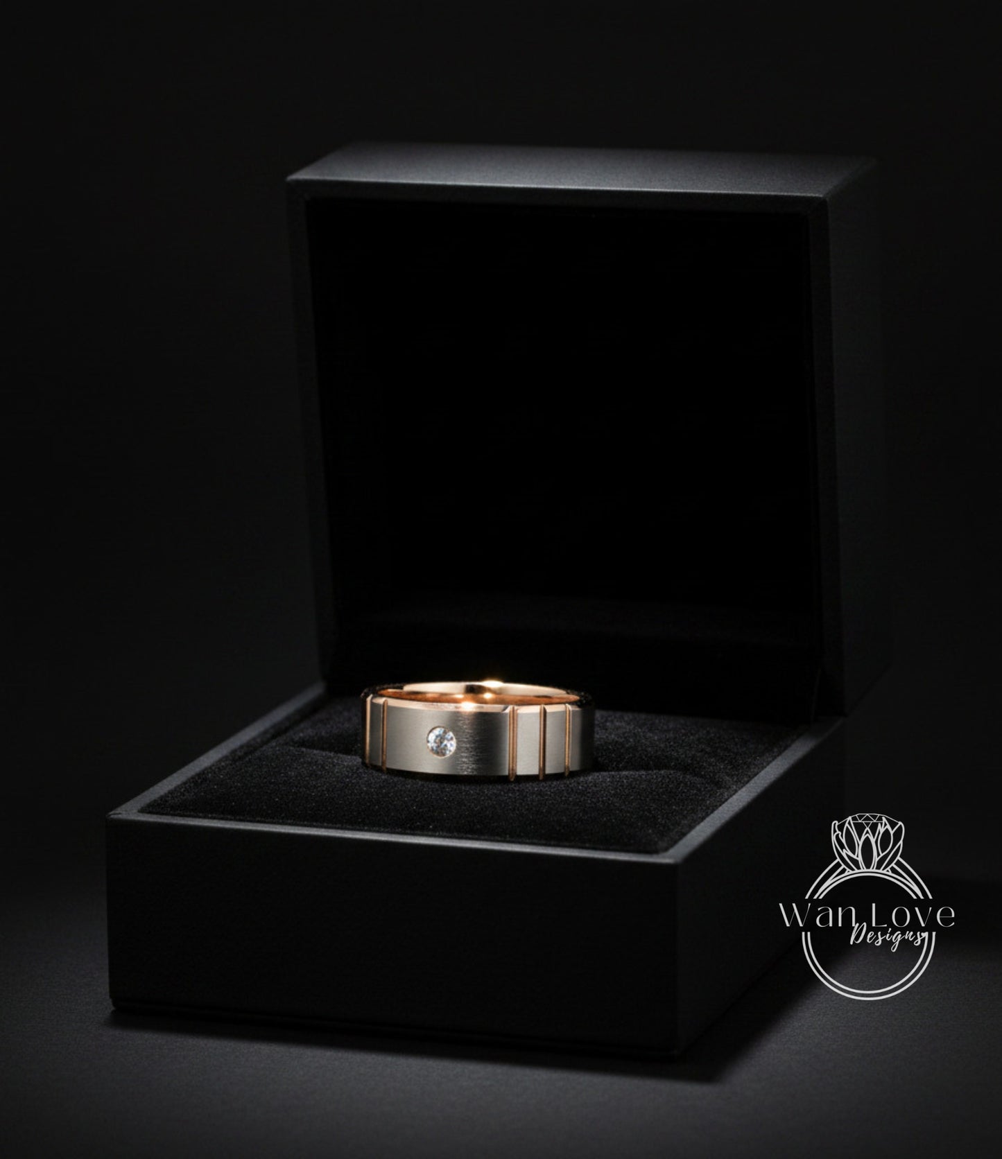 A gold ring with a diamond set in the center is displayed in a black jewelry box against a dark background.