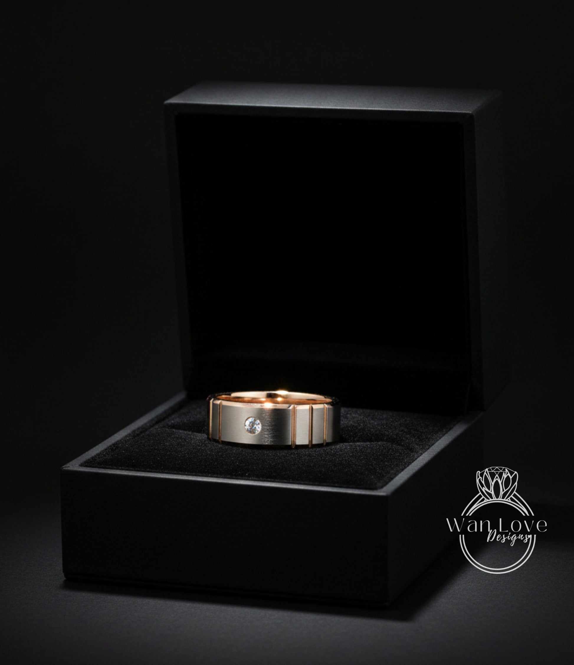 A gold ring with a diamond set in the center is displayed in a black jewelry box against a dark background.
