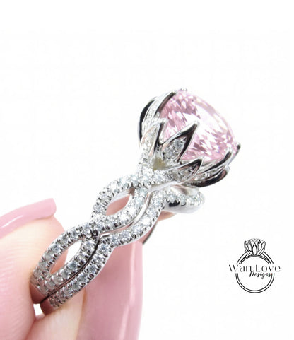 A close-up of a person's hand holding a diamond ring with a large pink gemstone.