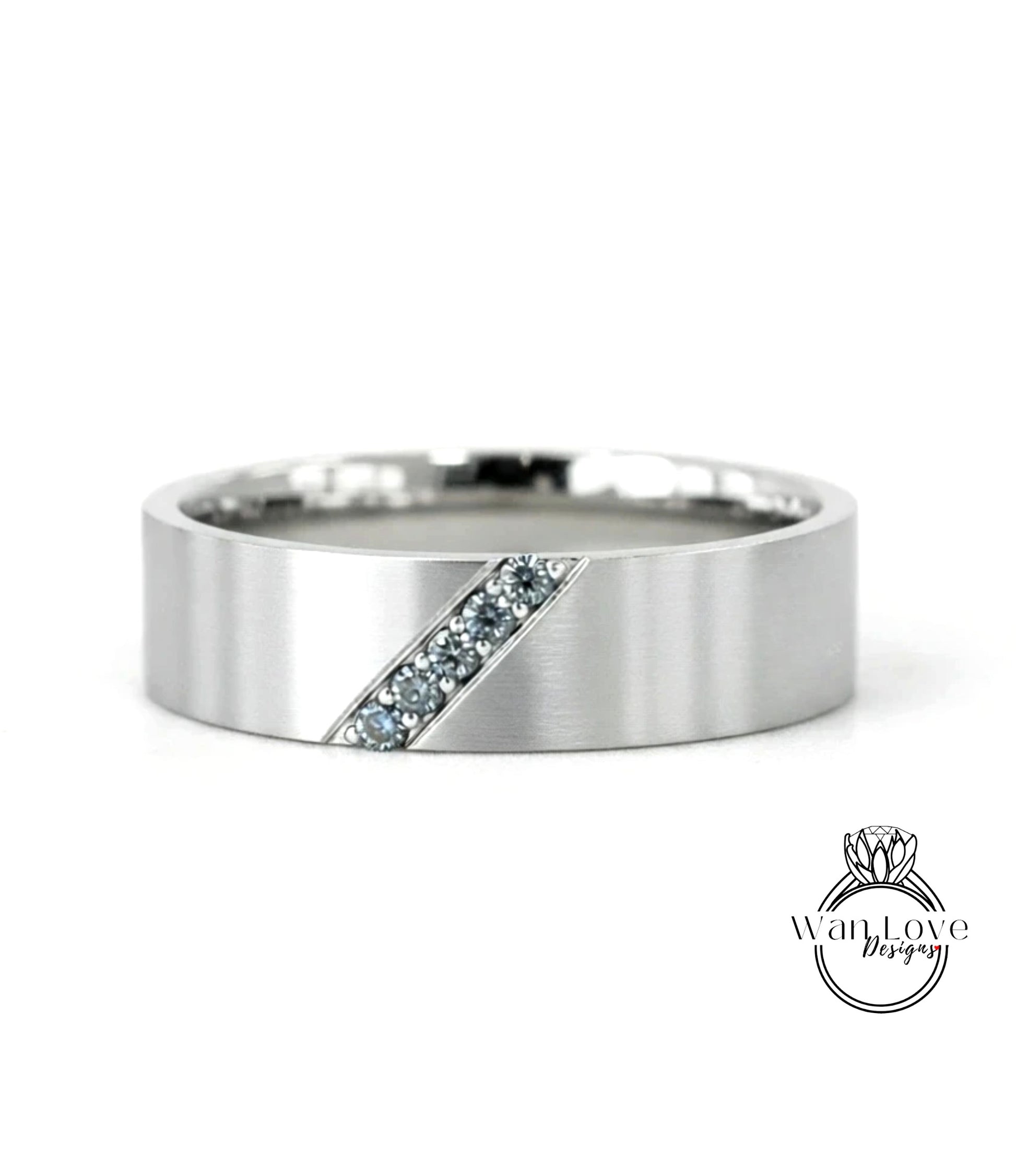 A silver-colored ring with a diagonal cut design and small blue gemstones set in it.