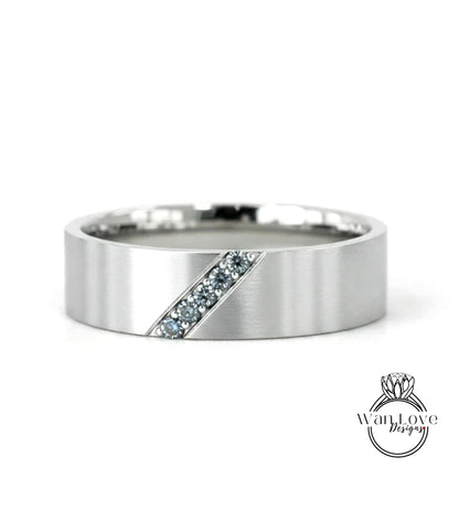 A silver-colored ring with a diagonal cut design and small blue gemstones set in it.