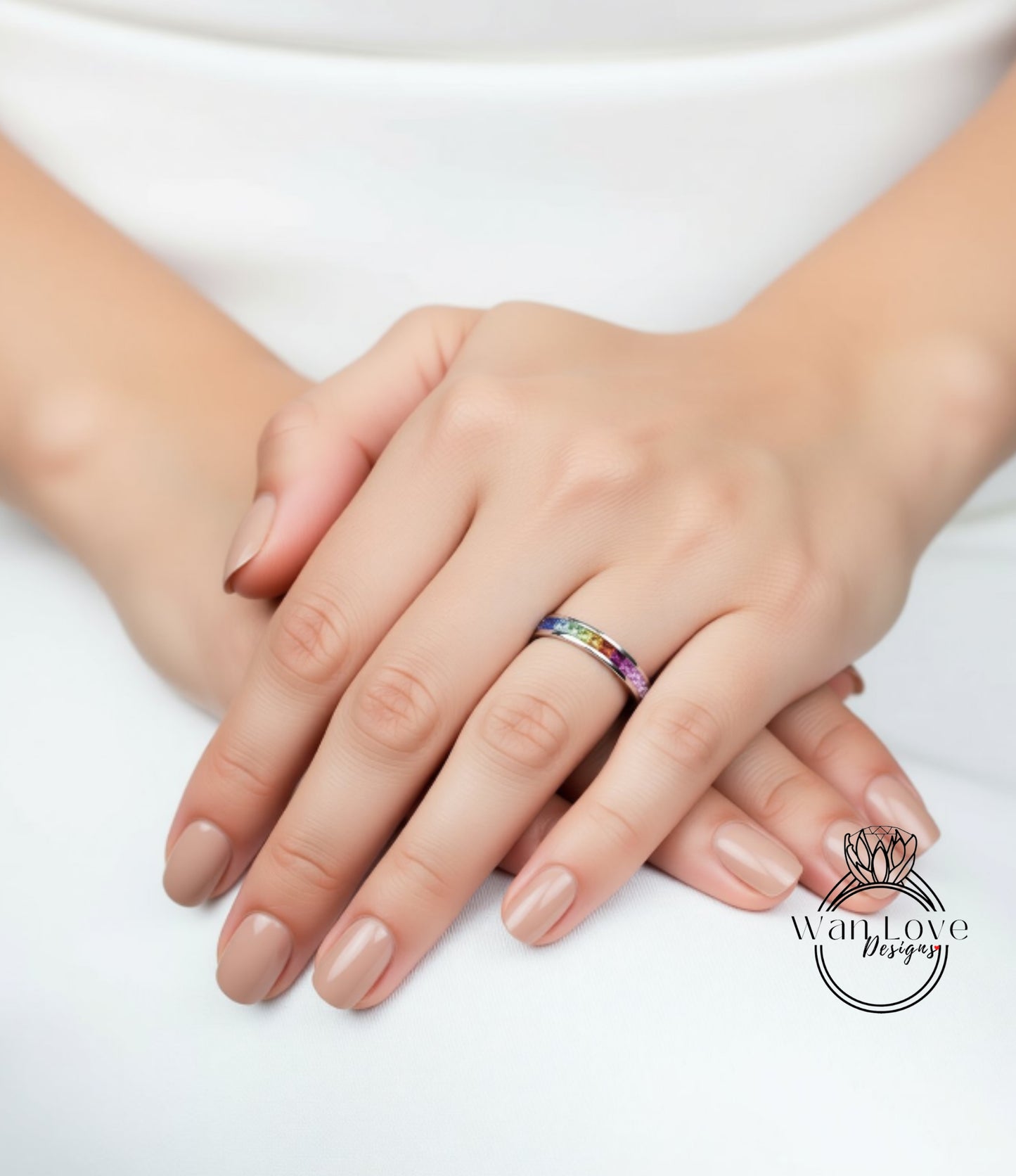 A close-up image of a person's hands resting on a surface, with a colorful ring visible on one of the fingers.
