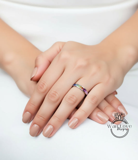 A close-up image of a person's hands resting on a surface, with a colorful ring visible on one of the fingers.