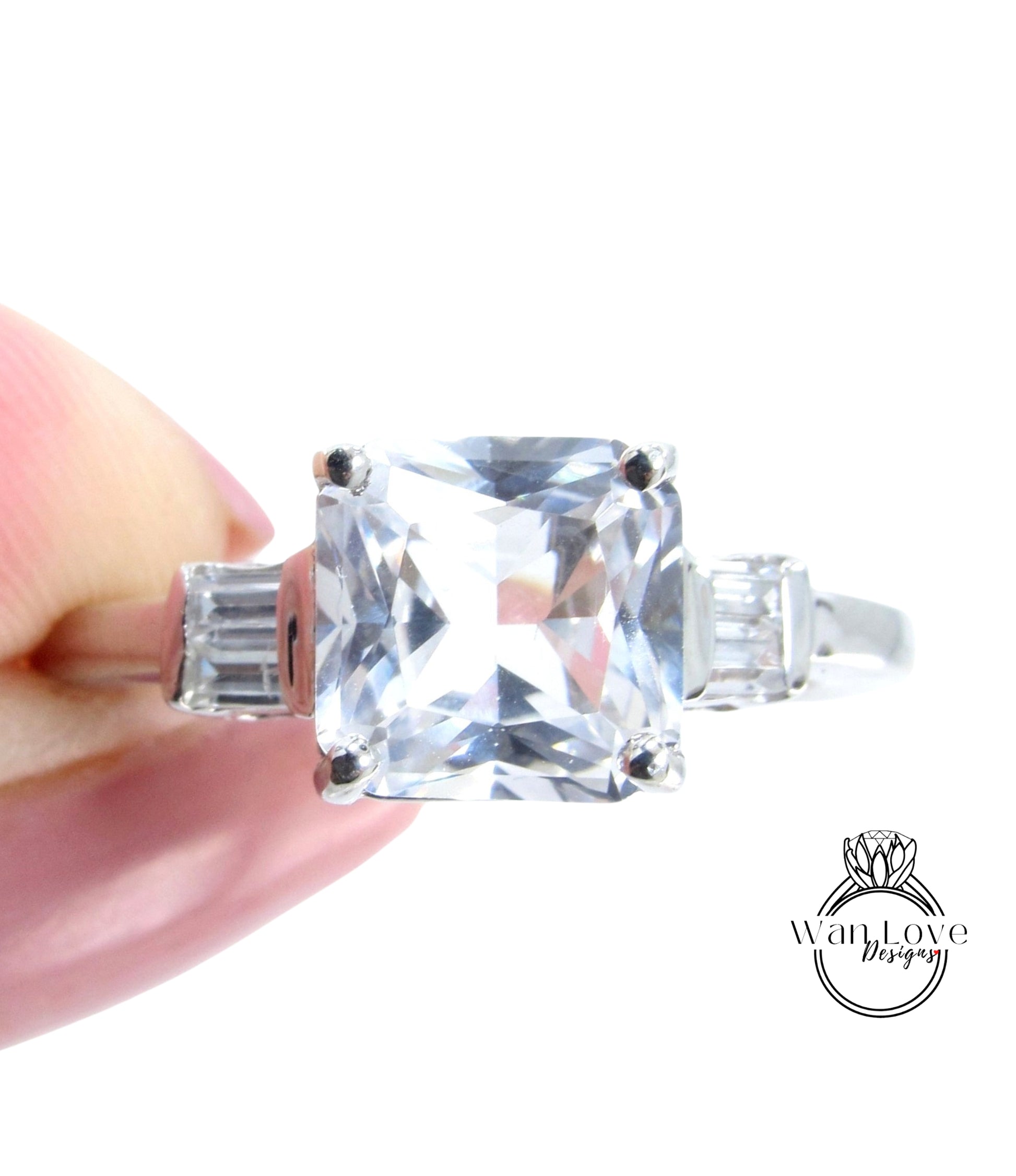A close-up image of a person's hand holding a large, clear gemstone ring with a diamond-like center stone.