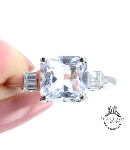 A close-up image of a person's hand holding a large, clear gemstone ring with a diamond-like center stone.