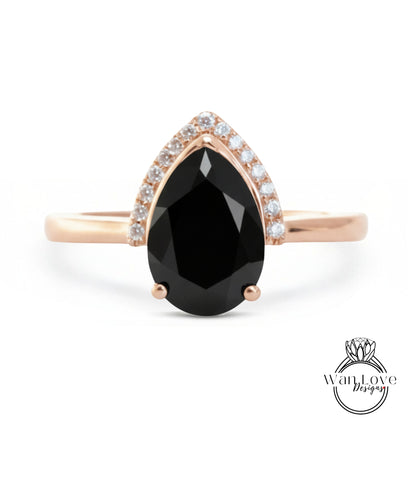 A gold ring with a large black gemstone, likely a diamond, set in the center.