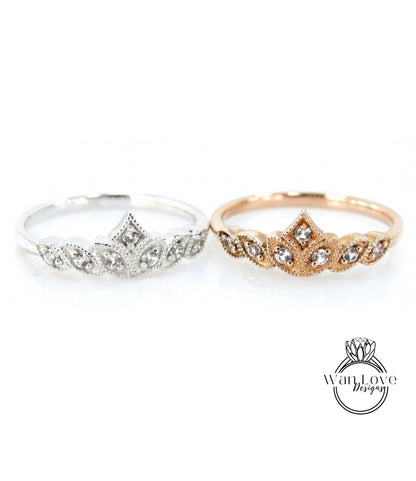 Two rings with a crown-like design, one silver and one gold, are displayed against a white background.