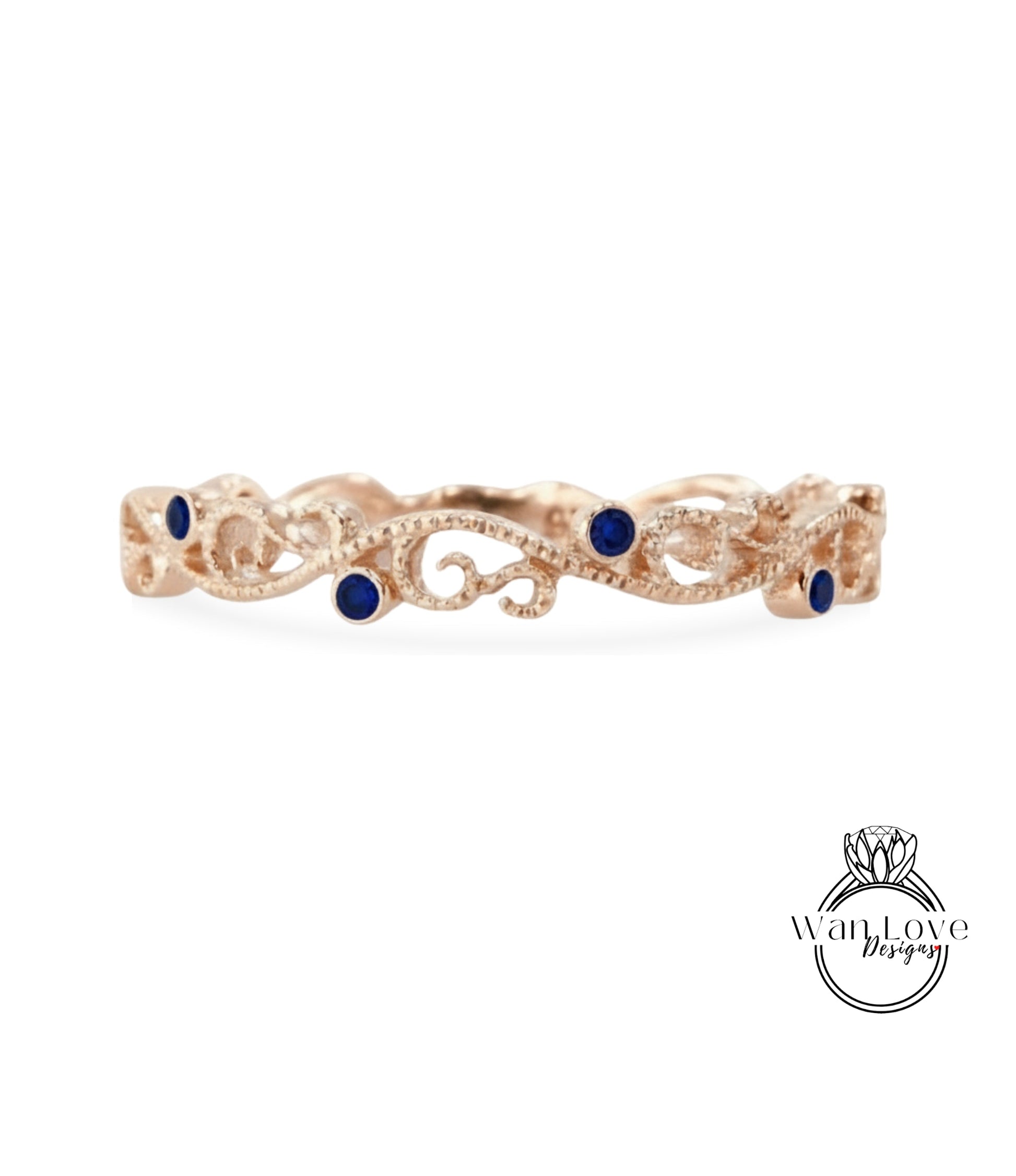 A rose gold ring with a decorative scroll design and blue gemstones.