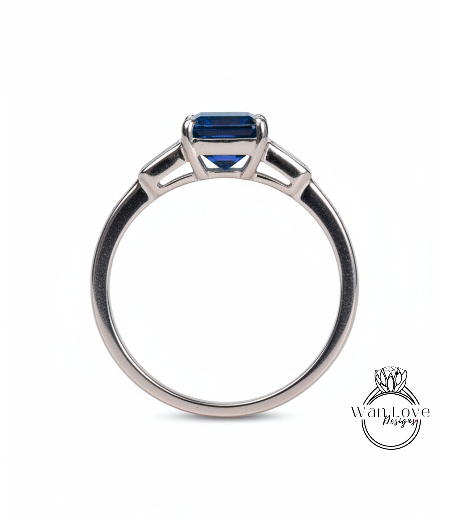 A silver engagement ring with a blue gemstone, possibly a sapphire, set in a three-pronged design.