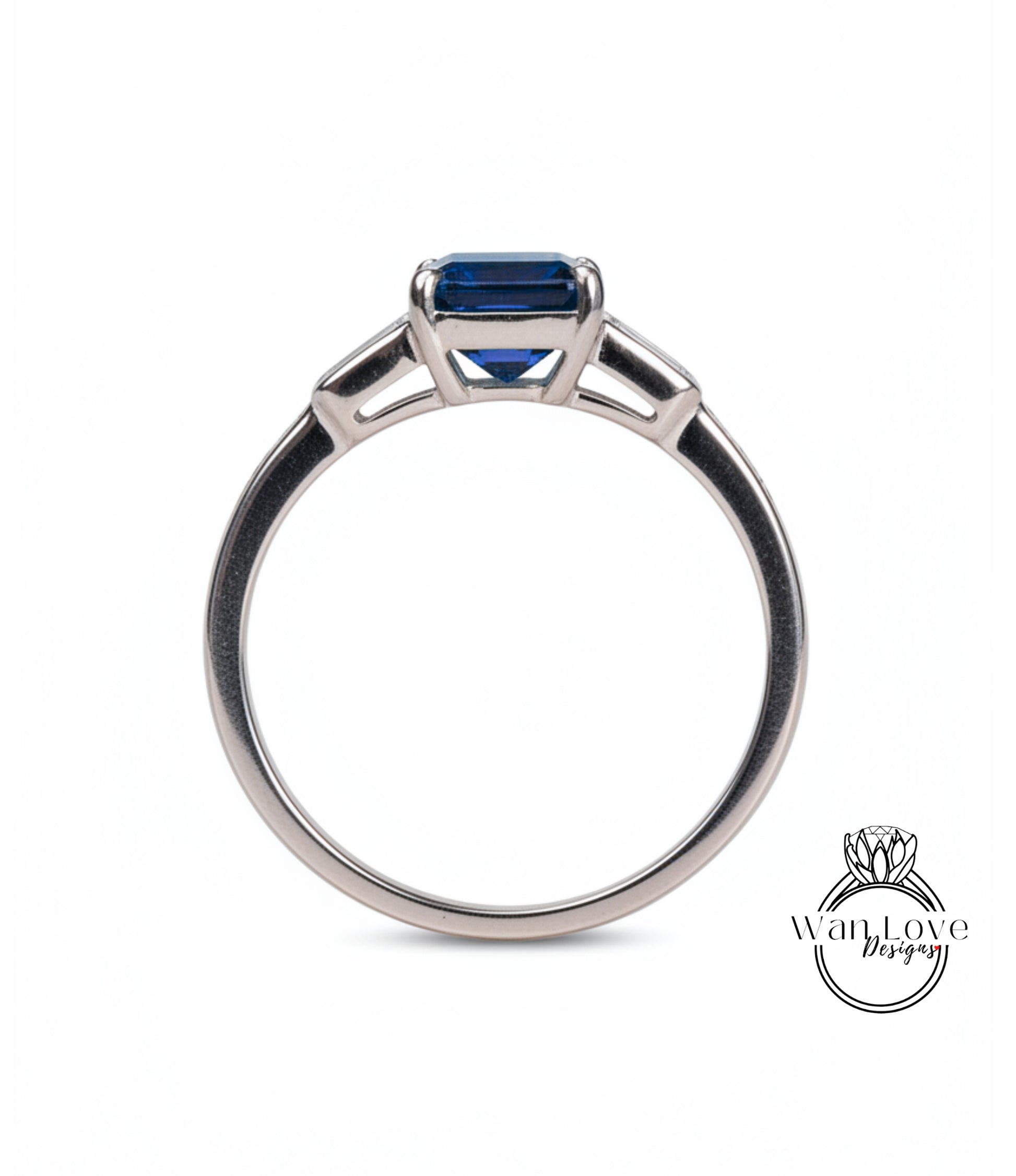 A silver engagement ring with a blue gemstone, possibly a sapphire, set in a three-pronged design.