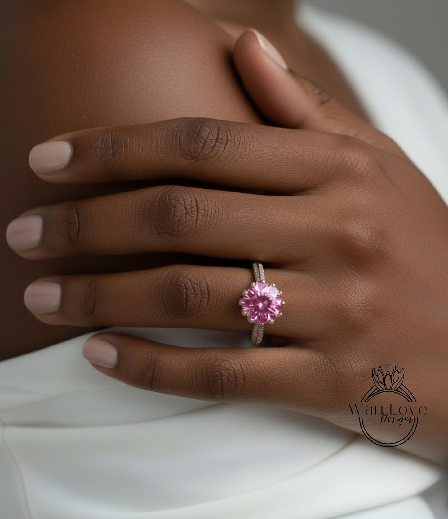 A close-up of a person's hand wearing a pink diamond ring.