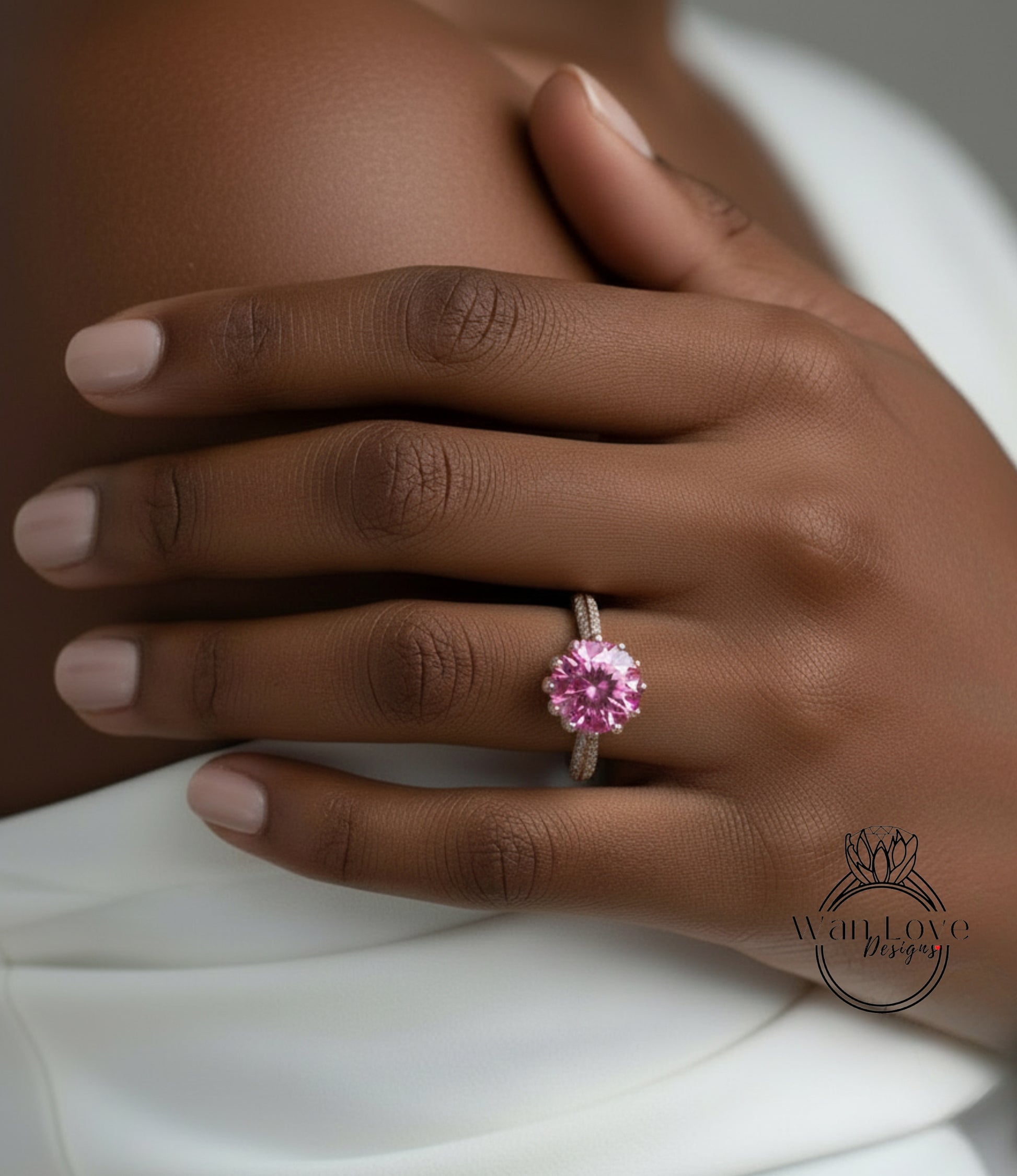 A close-up of a person's hand wearing a pink diamond ring.