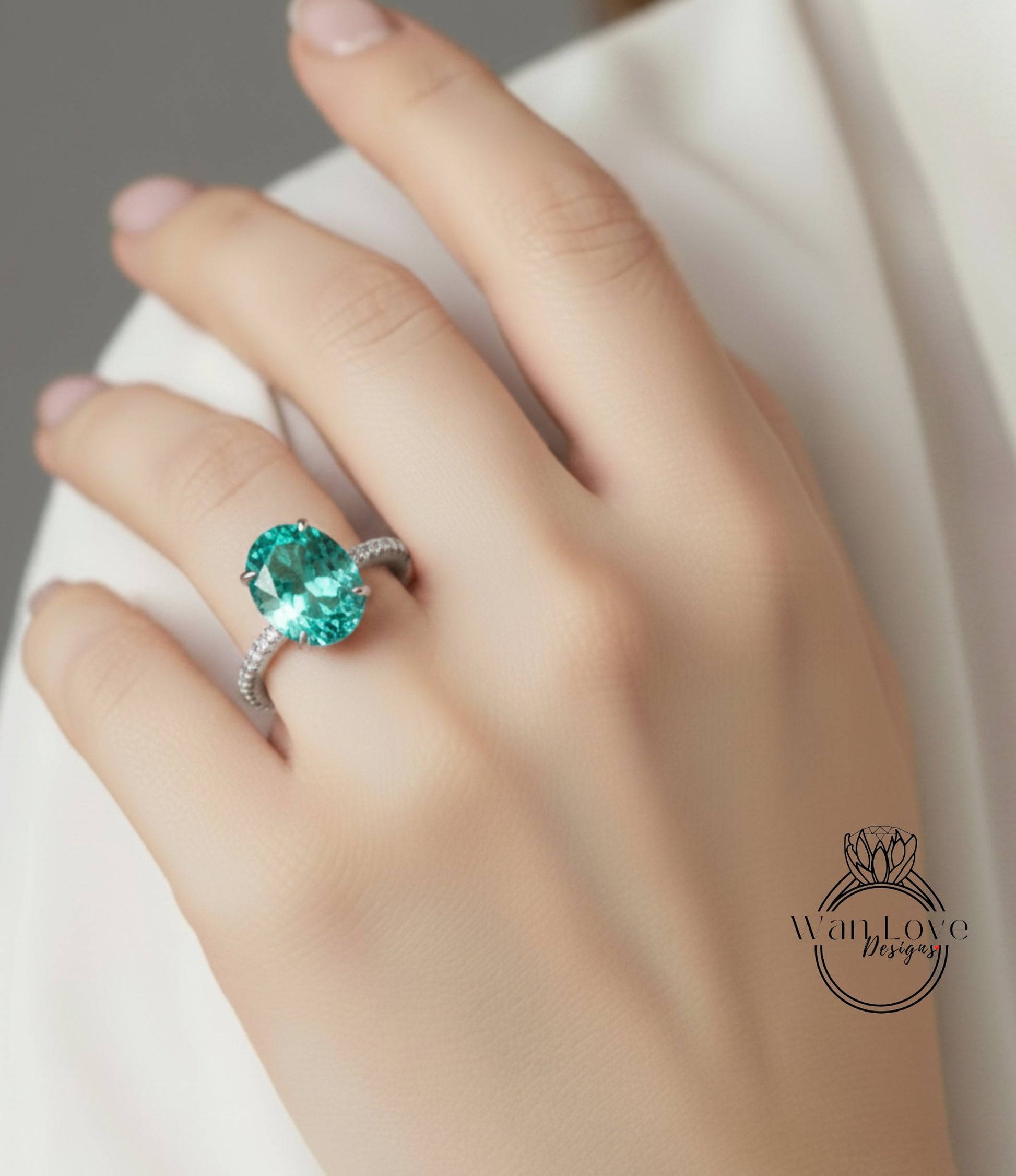 A close-up of a hand wearing a ring with a large, oval-shaped green gemstone.