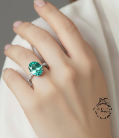 A close-up of a hand wearing a ring with a large, oval-shaped green gemstone.