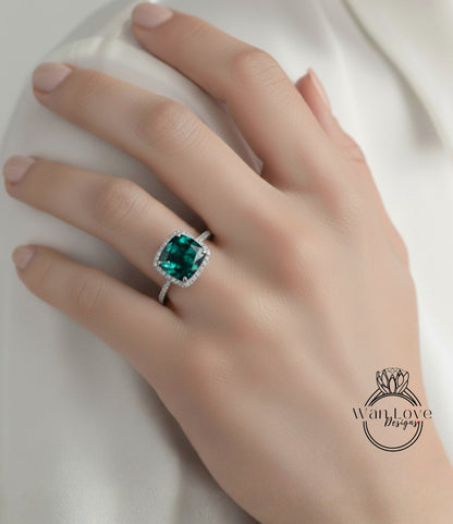 A close-up of a hand wearing a ring with a large, green gemstone.