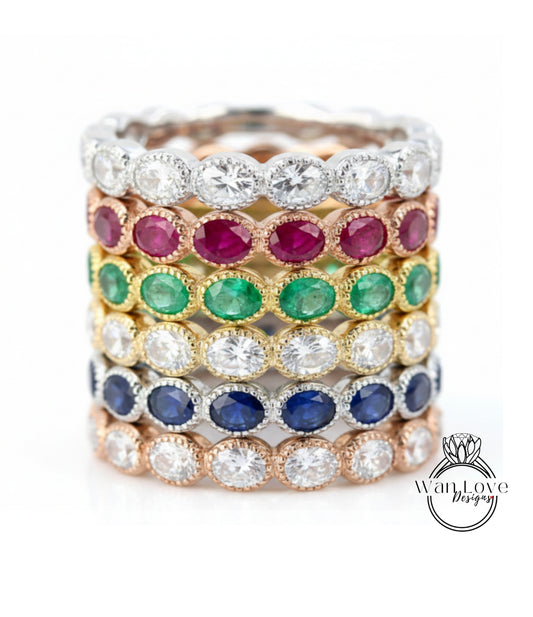 A stack of rings with various colored gemstones, including diamonds and rubies, set in a silver band.
