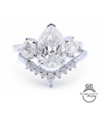 A close-up image of a diamond engagement ring with a large pear-shaped diamond at the center, surrounded by smaller diamonds on either side.