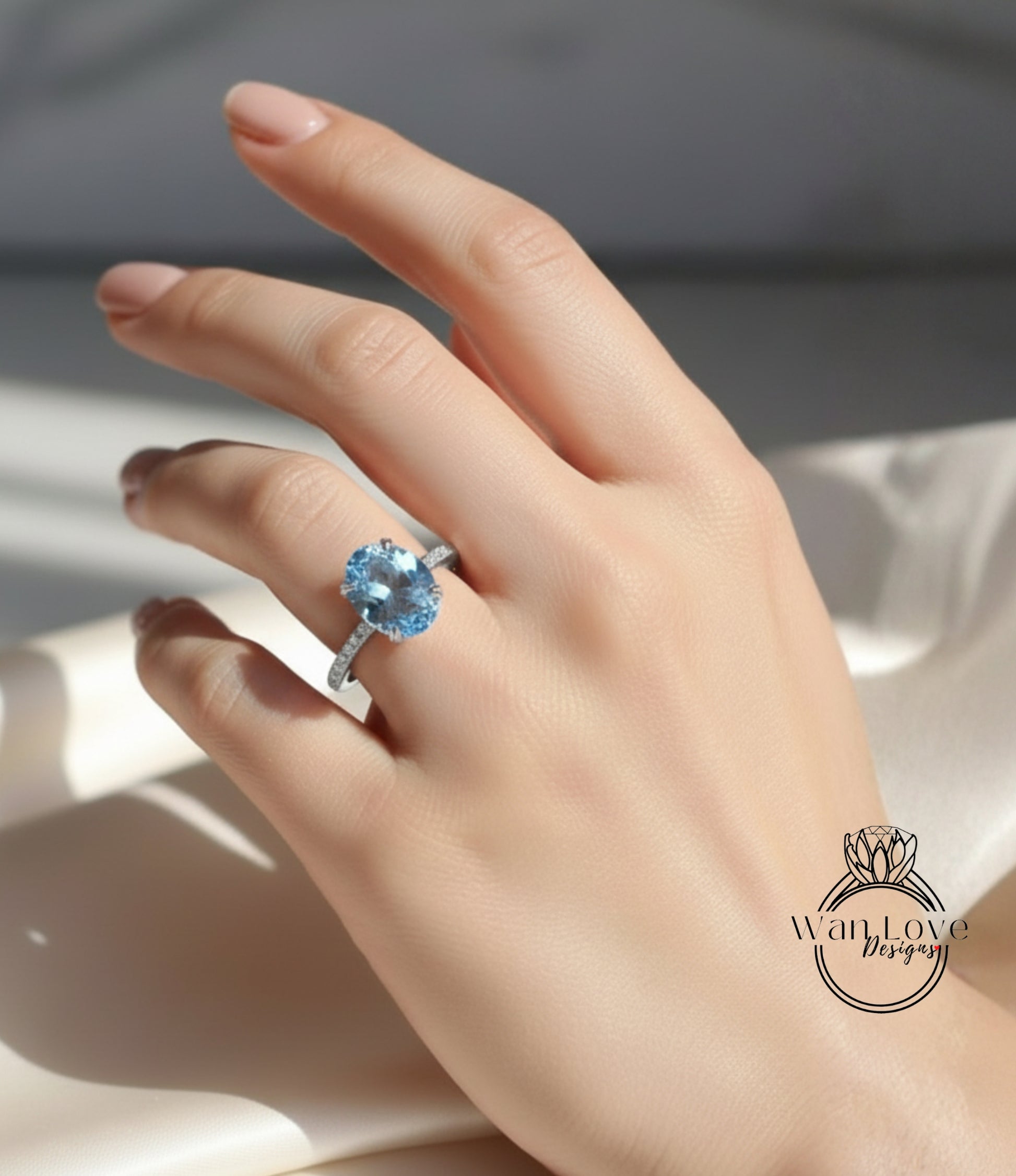 A close-up of a hand wearing a ring with a large blue gemstone, likely an aquamarine or blue topaz stone.