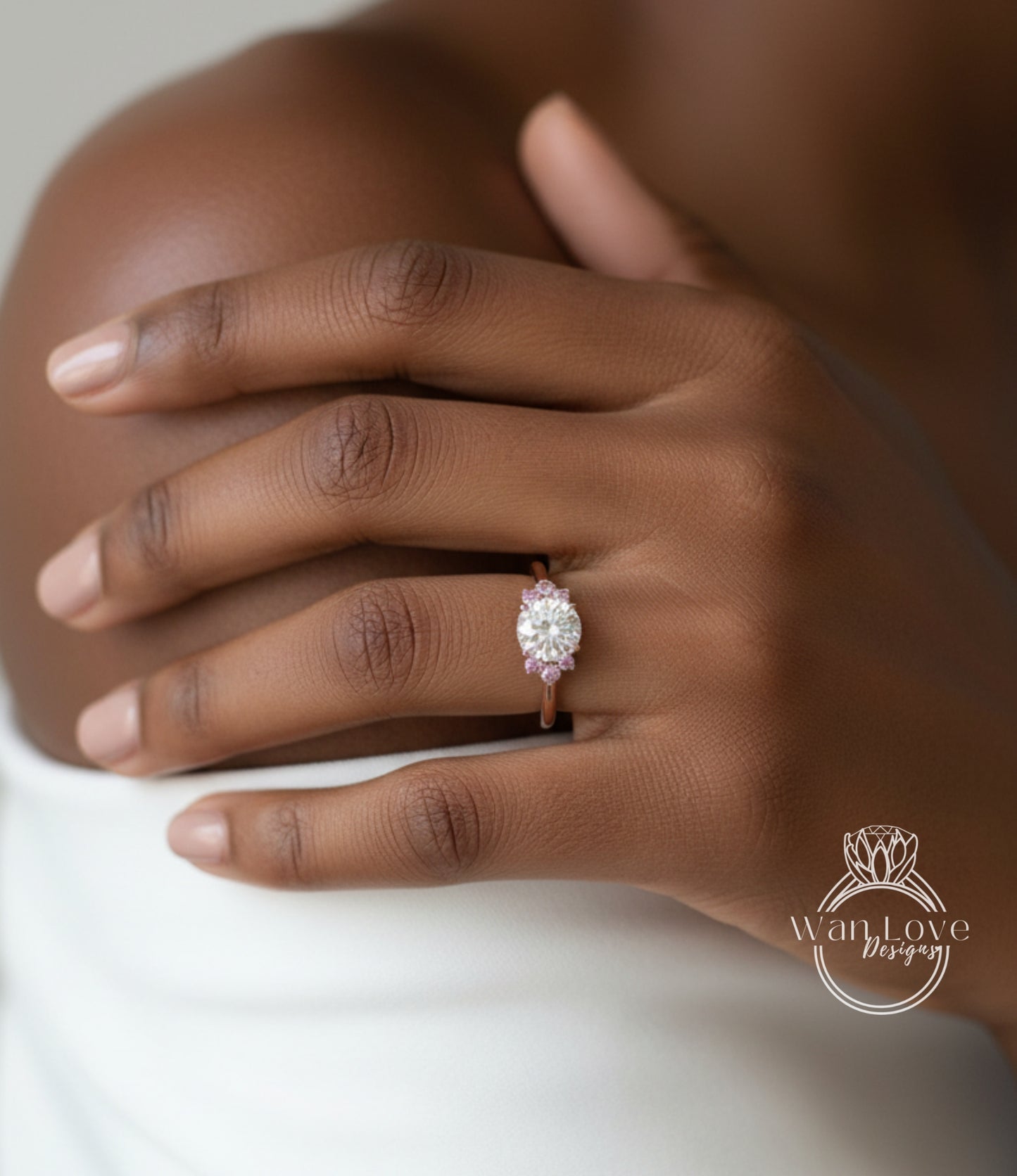 A close-up of a person's hand wearing a diamond engagement ring with a large central diamond surrounded by smaller diamonds.