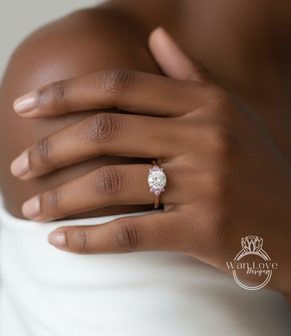 A close-up of a person's hand wearing a diamond engagement ring with a large central diamond surrounded by smaller diamonds.