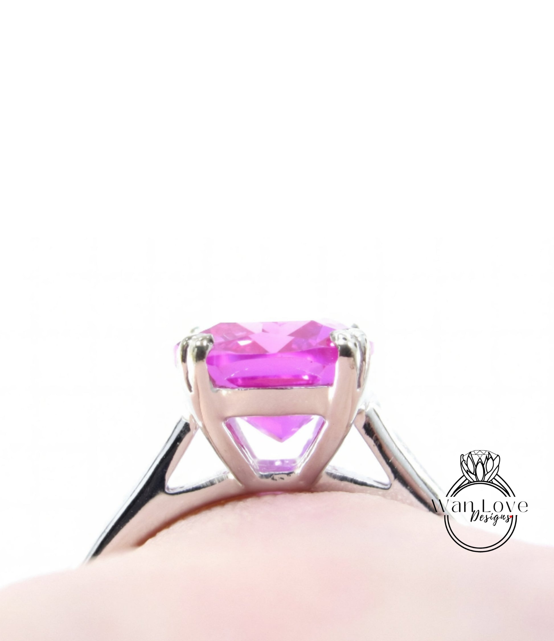 A close-up view of a silver ring with a large, vibrant pink gemstone set in the center.