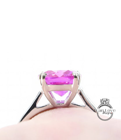 A close-up view of a silver ring with a large, vibrant pink gemstone set in the center.