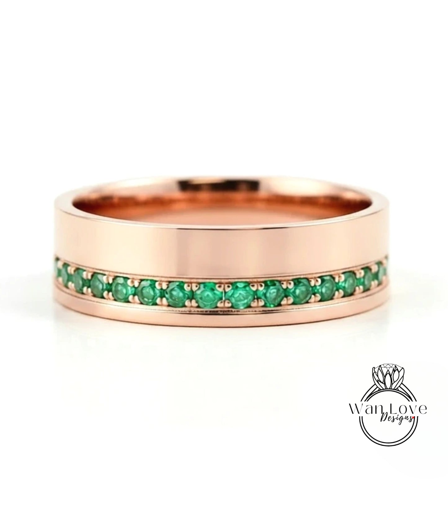 A rose gold band with a row of green gemstones set in it.