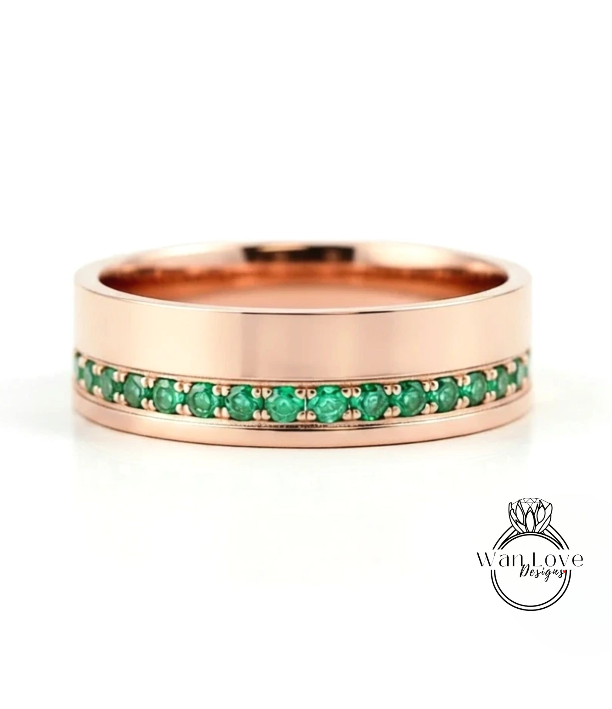A rose gold band with a row of green gemstones set in it.