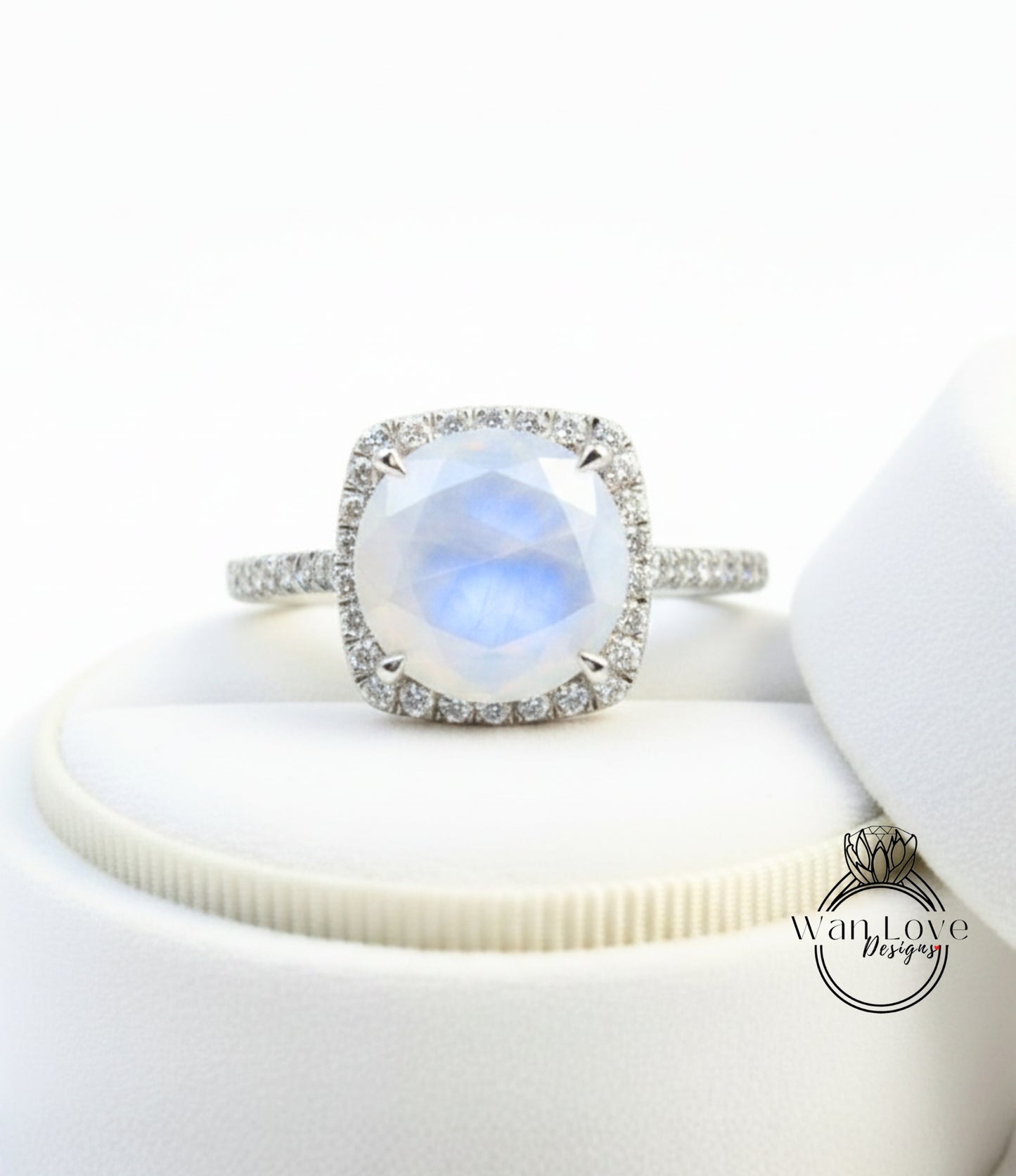 A diamond ring with a large, round, blue gemstone set in a halo of smaller diamonds, placed on a white surface.