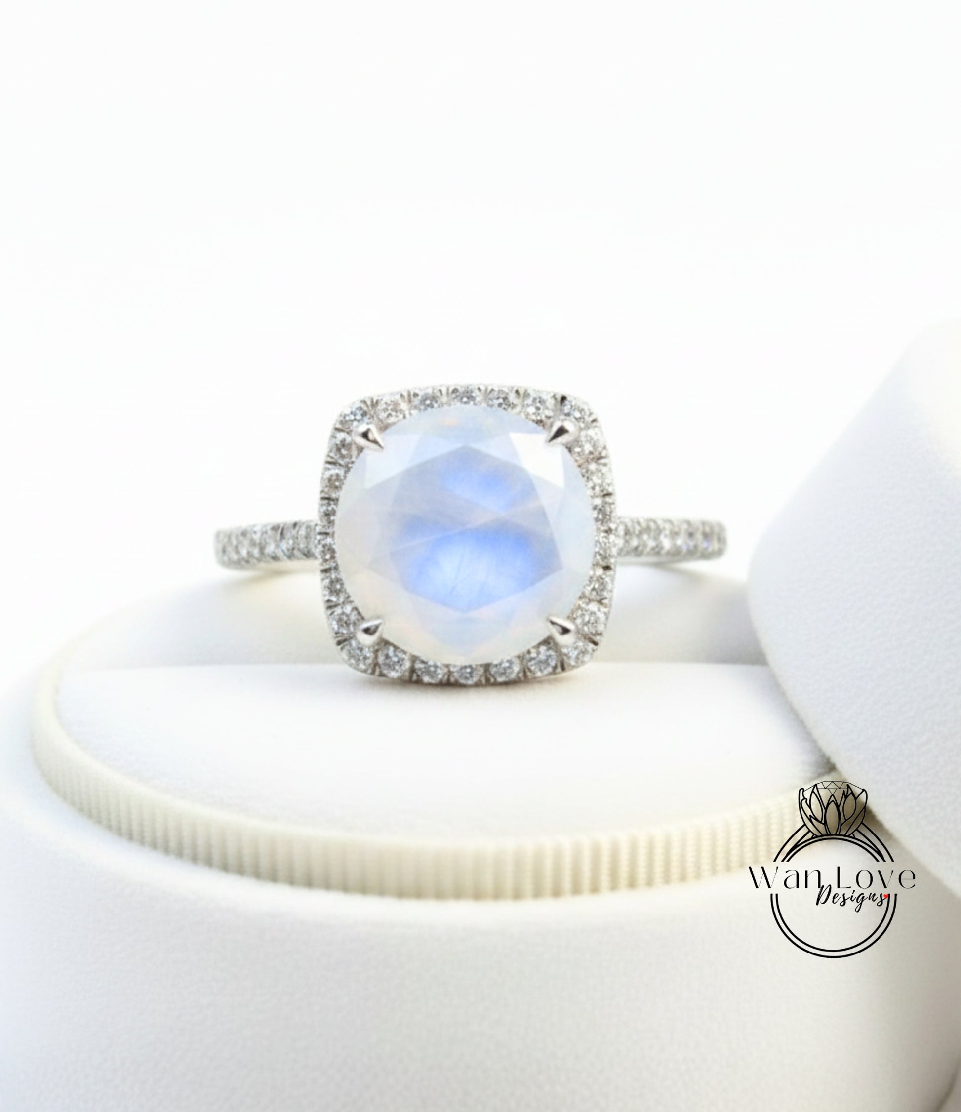 A diamond ring with a large, round, blue gemstone set in a halo of smaller diamonds, placed on a white surface.
