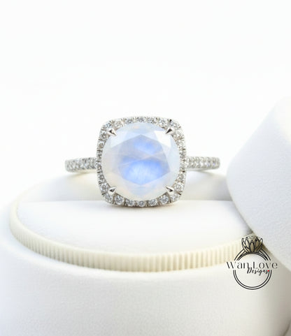 A diamond ring with a large, round, blue gemstone set in a halo of smaller diamonds, placed on a white surface.